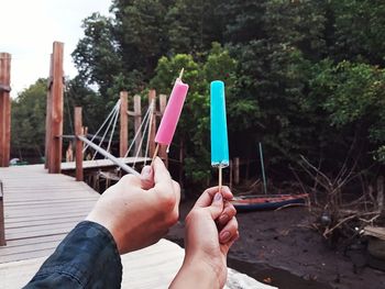 Low section of woman holding paper against trees