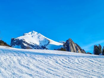 Snow covered mountain against blue sky