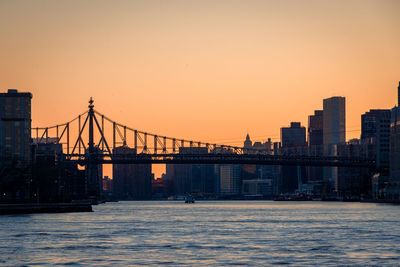Suspension bridge over river against sky during sunset