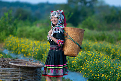 Woman holding umbrella while standing on field