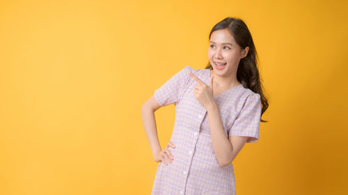 Portrait of a smiling young woman over yellow background