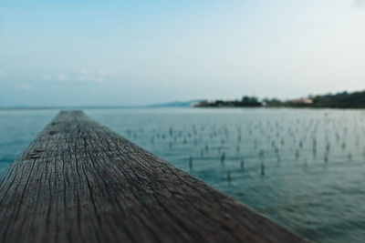 Close-up of pier over lake against sky
