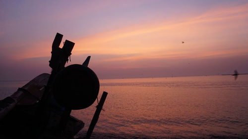 Silhouette camera on beach against sky during sunset