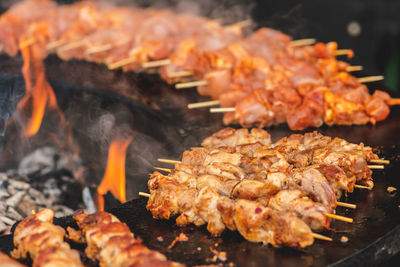 Preparing chicken meat skewers, grilled or roasted in a barbecue on an open fire and flames