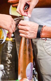 Cropped image of man opening wine bottle