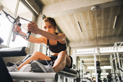 Low angle view of young woman exercising in gym