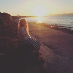 Woman sitting on beach looking at sunset