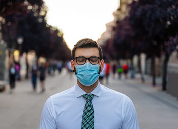 Portrait of young man standing on street in city