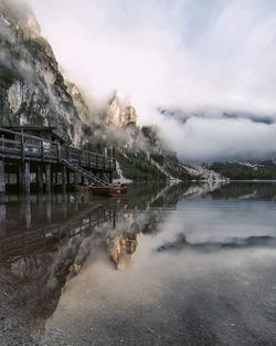 Mountains reflecting on calm lake during foggy weather