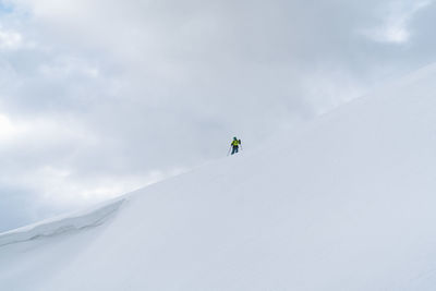 Low angle view of man standing on snowcapped mountain against sky