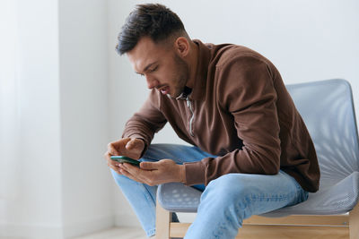 Young man using laptop while sitting on sofa at home