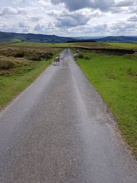 Road amidst field against sky