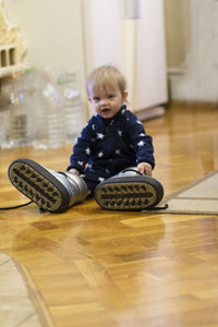 Boy sitting on hardwood floor at home