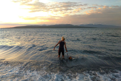 Full length of man on beach against sky during sunset