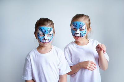 Two sister girls with aqua makeup in the form of a blue water zodiac tiger depict a tiger.