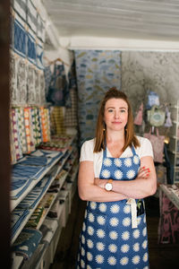 Portrait of confident woman standing with arms crossed in fabric shop