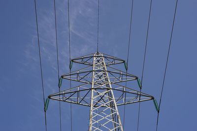 Low angle view of electricity pylon against blue sky