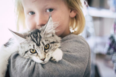 Close-up portrait of girl carrying cat at home