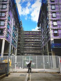 Man walking on modern office building against sky