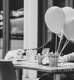 Midsection of woman holding balloons on table at home