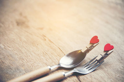 High angle view of cutleries with heart shape clothespins on wooden table