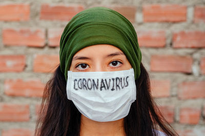 Portrait of young woman against wall