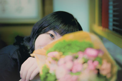 Portrait of woman holding flower at home