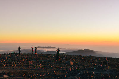 People on mountain against sky during sunset