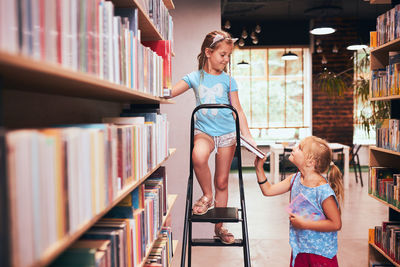 Two schoolgirls spending time in school library. primary school students learning from books