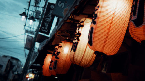 Low angle view of illuminated lanterns hanging by building at night