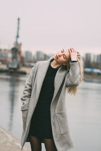 Young woman standing at harbor against sky