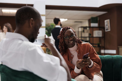 Side view of female friends using mobile phone while sitting at home