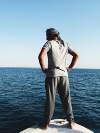 Rear view of man standing in sea against clear sky