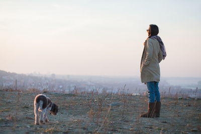 Full length of man standing with dog on field