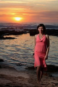 Portrait of woman standing on beach during sunset
