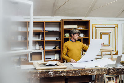 Craftsman looking at blueprint in studio