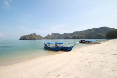 Boats moored on beach against sky