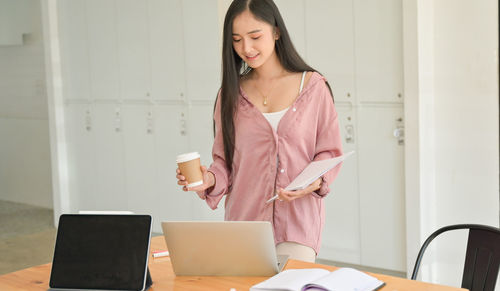 Young woman using mobile phone in laptop