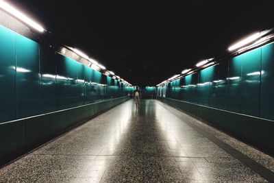 Rear view of passenger walking in illuminated subway tunnel