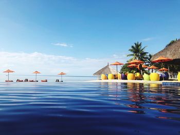 Swimming pool by sea against blue sky