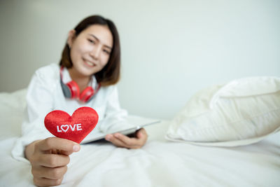 Woman holding heart shape on bed
