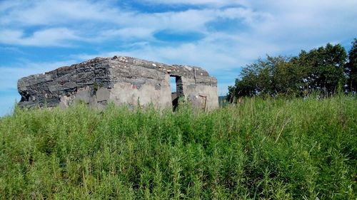 Abandoned built structure on field against sky