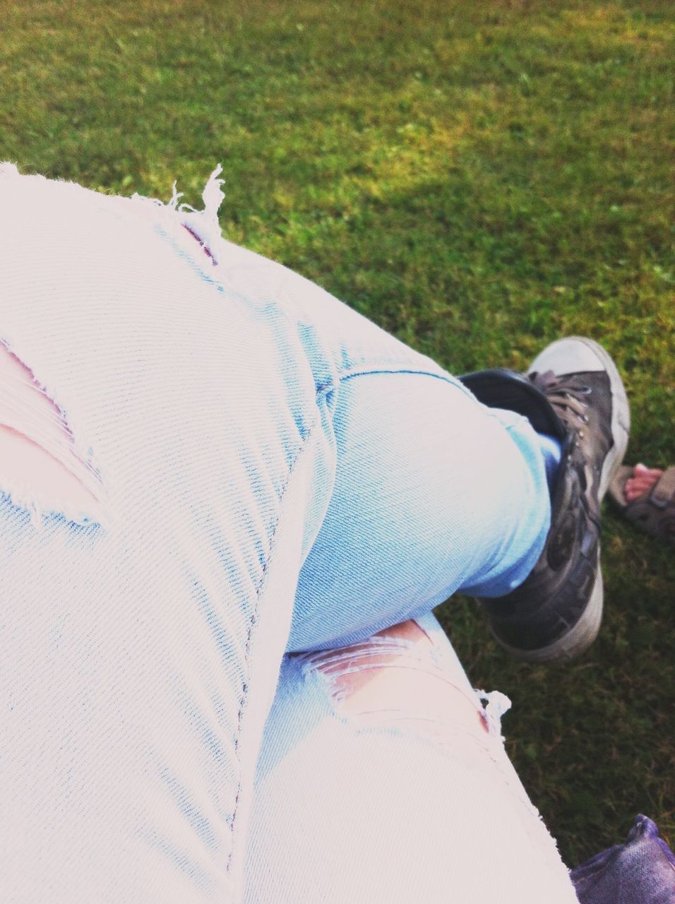 lifestyles, leisure activity, grass, low section, relaxation, person, field, sitting, casual clothing, lying down, resting, shoe, young adult, day, relaxing, outdoors, sunlight