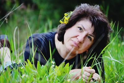 Portrait of mature woman relaxing on grassy field at park