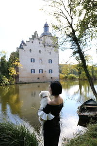 Rear view of woman standing by lake against sky