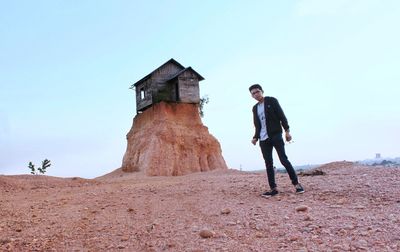 Portrait of man standing against house on rock formation