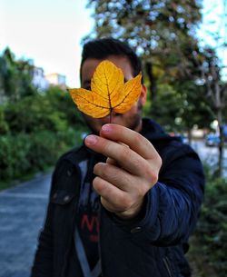 Portrait of person holding plant during autumn