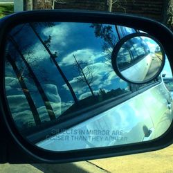 Reflection of clouds in side-view mirror