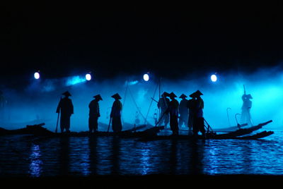 Silhouette men standing on boat in lake at night