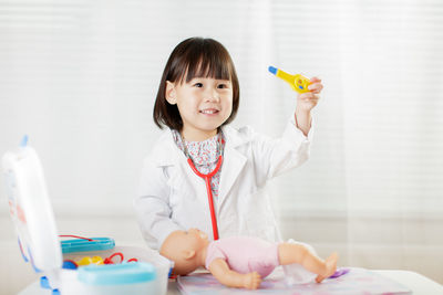 Portrait of cute girl holding toy at home